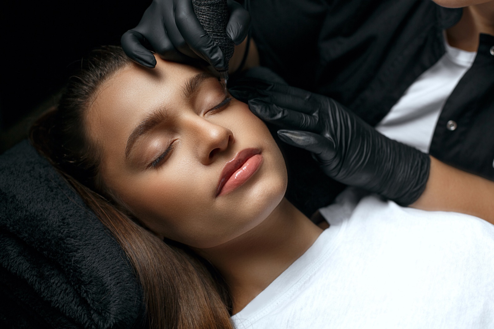 Permanent Make-up an der Augenbraue, Arbeit mit schwarzen Handschuhen (Symbolbild)
